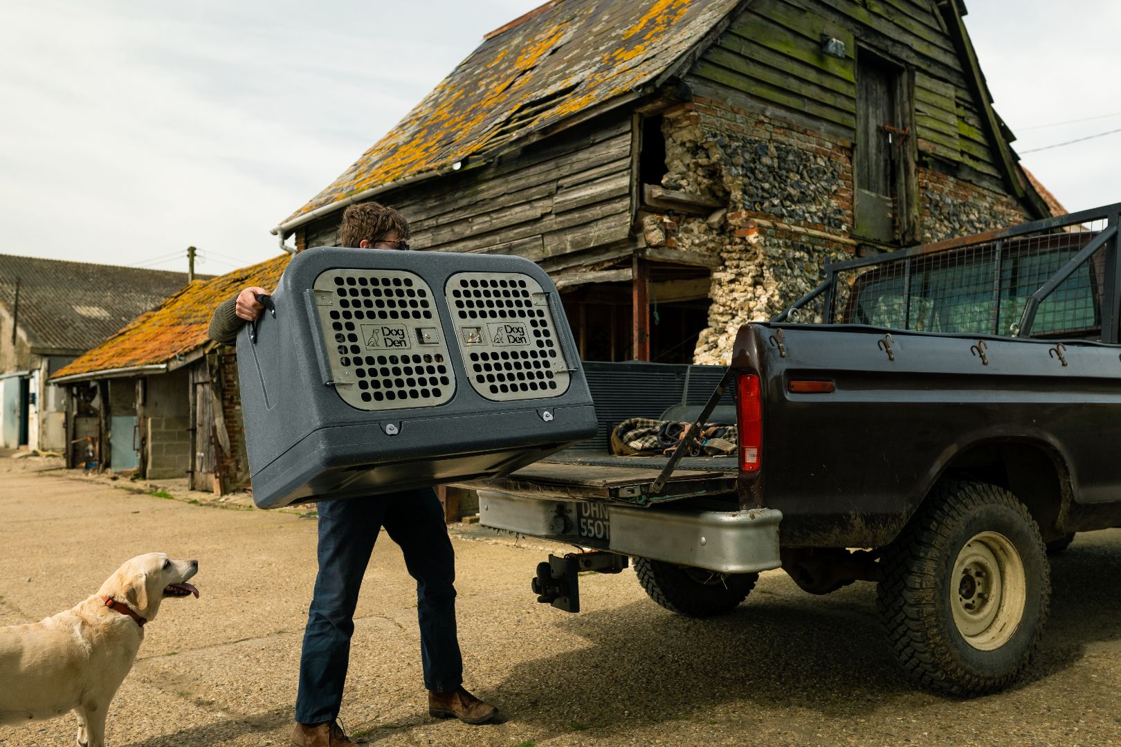 gunmetal dog den being lifted into an old ford in the farmyard